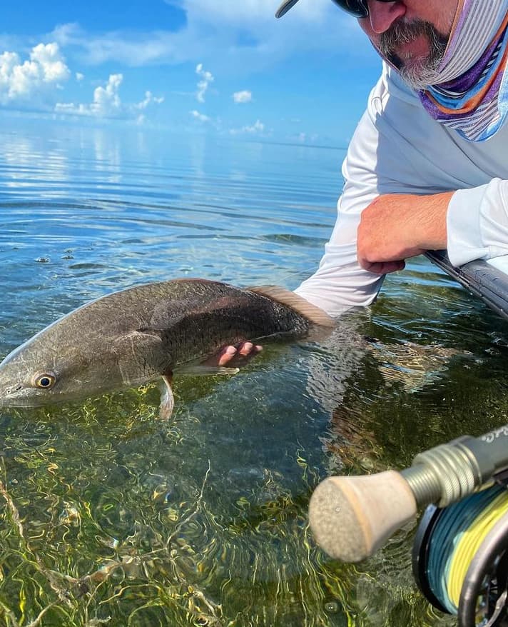 An image of a fisherman with a redfish on a full day Hot Water Fishing Charter